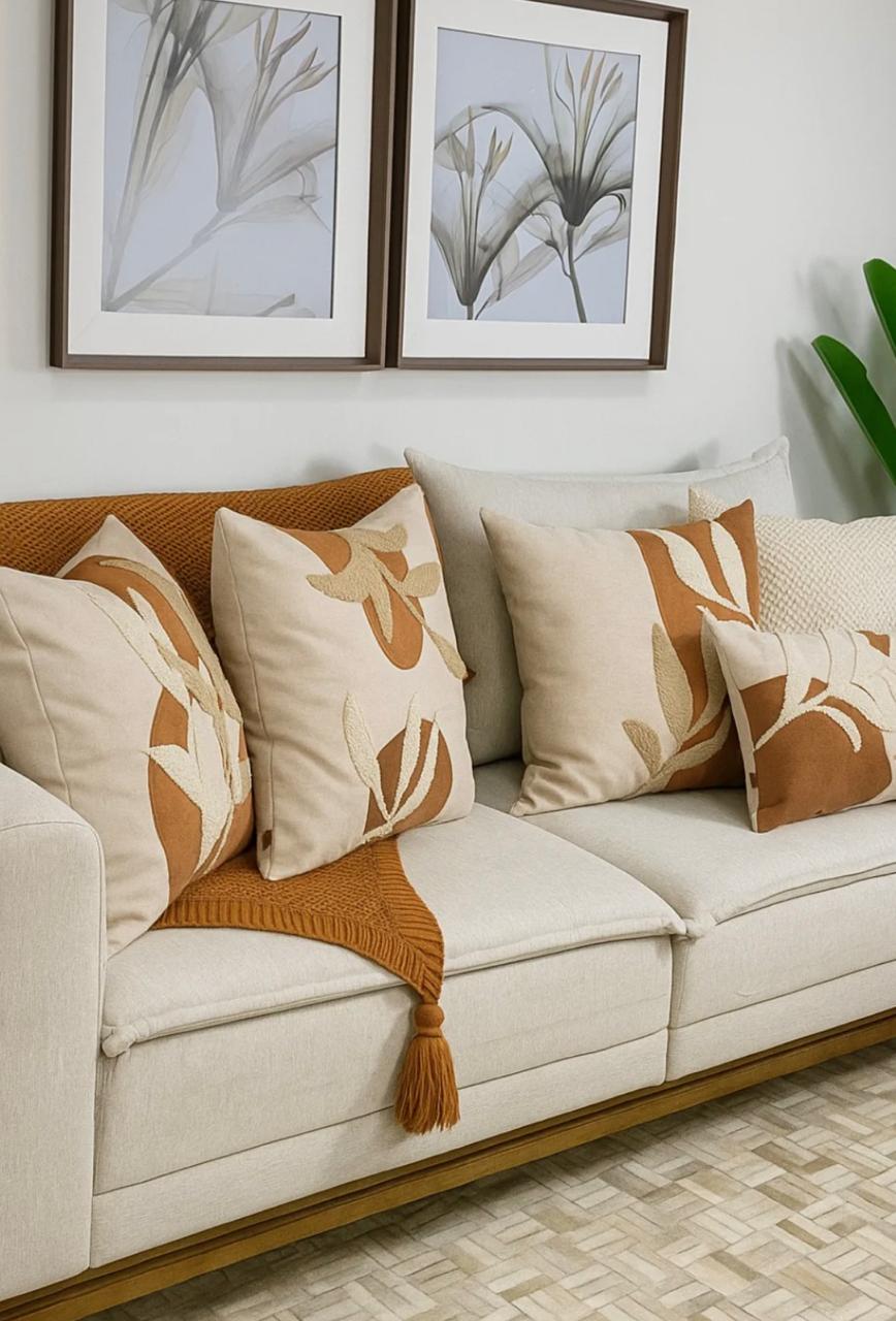 Sofá com almofadas bordadas e quadros botânicos